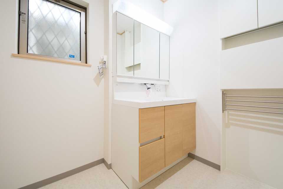 明るいメープル調の洗面化粧台と白のクロスが明るく清潔感ある洗面室を演出。