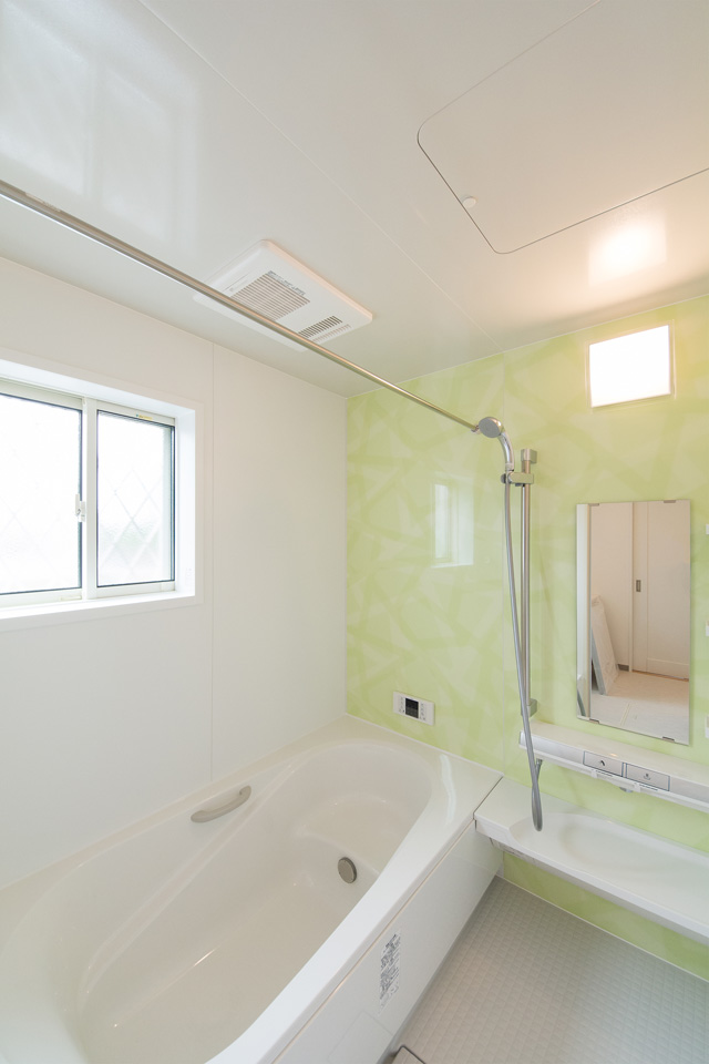 ミントグリーンのアクセントパネルで、爽やかな空間のバスルーム。