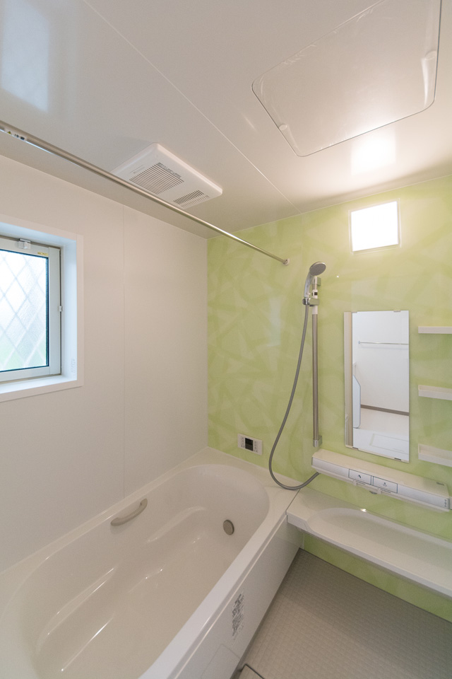 ミントグリーンのアクセントパネルで、爽やかな空間のバスルーム。