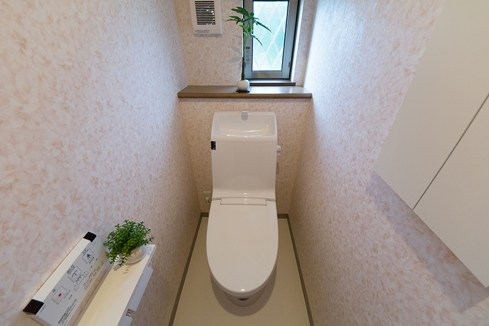 白を基調とした清潔感のある1階トイレ。ライトピンクの花柄のアクセントクロスがエレガントな印象をプラス。