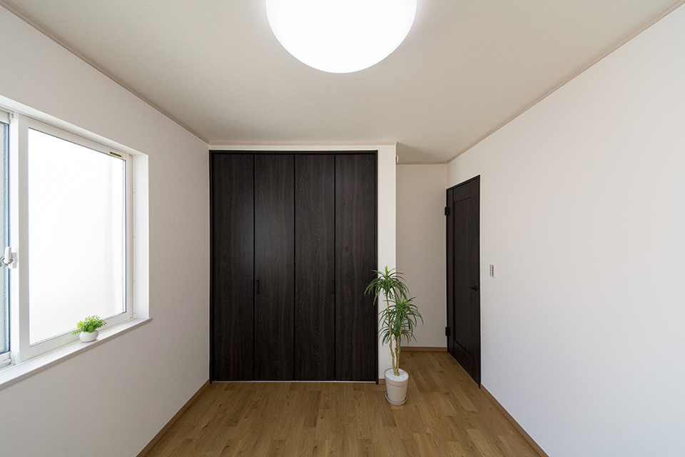 アッシュのフローリングとスモークオークの建具がナチュラルな空間を演出する2階洋室。