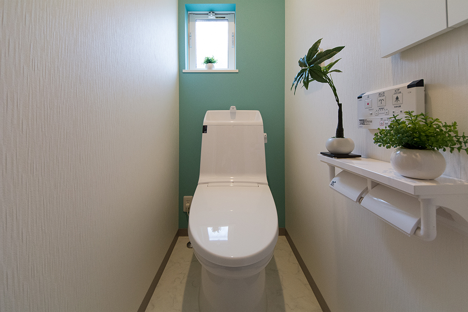 爽やかな印象を与えるターコイズブルーのアクセントクロスが印象的な1階トイレ。