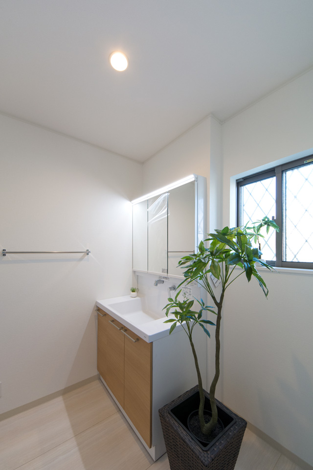 白を基調とした清潔感のあるサニタリールーム。木目調の洗面化粧台扉がナチュラルな雰囲気を演出します。