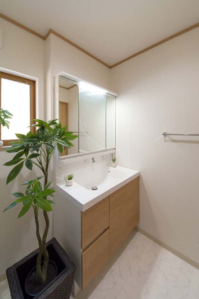 白を基調とした清潔感のあるサニタリールーム。木目調の洗面化粧台がナチュラルな空間を演出。