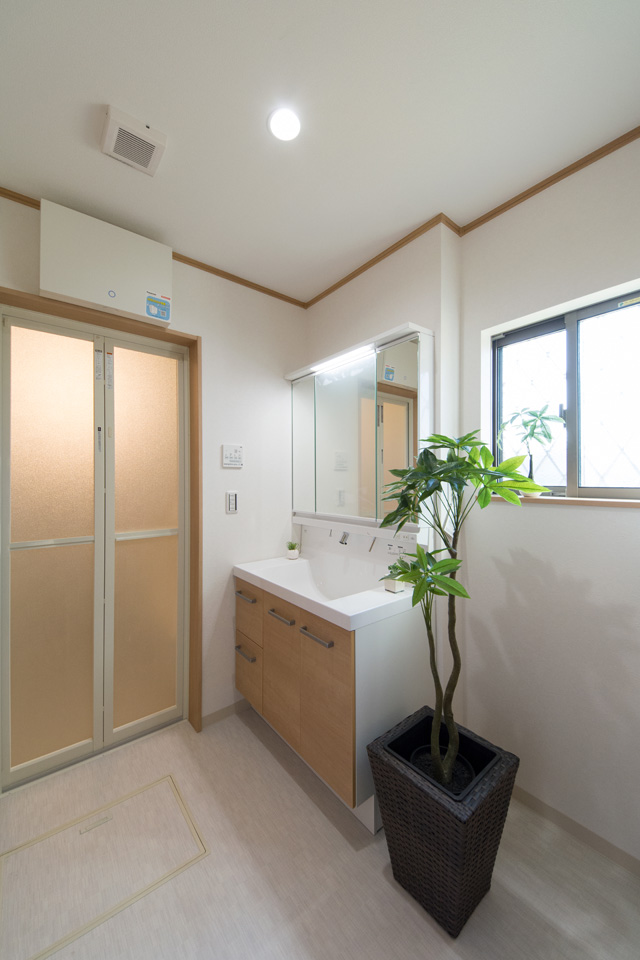 白を基調とした清潔感のあるサニタリールーム。木目調の洗面化粧台がナチュラルな空間を演出。