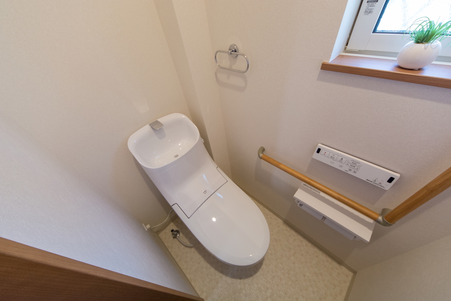 白を基調とした清潔感のある1Fトイレ。手すり設置で安全で快適な暮らしをサポート。