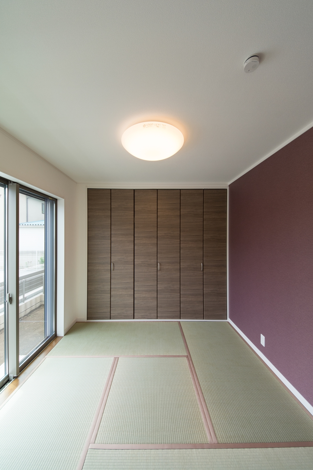 畳の爽やかなグリーン、あずき色のクロス、ブラウンの建具が空間を彩る1階畳敷きスペース。