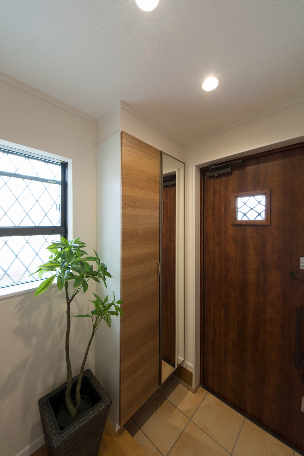 アンティーク調の玄関扉とベージュのテラコッタ調タイルがナチュラルな雰囲気を演出。