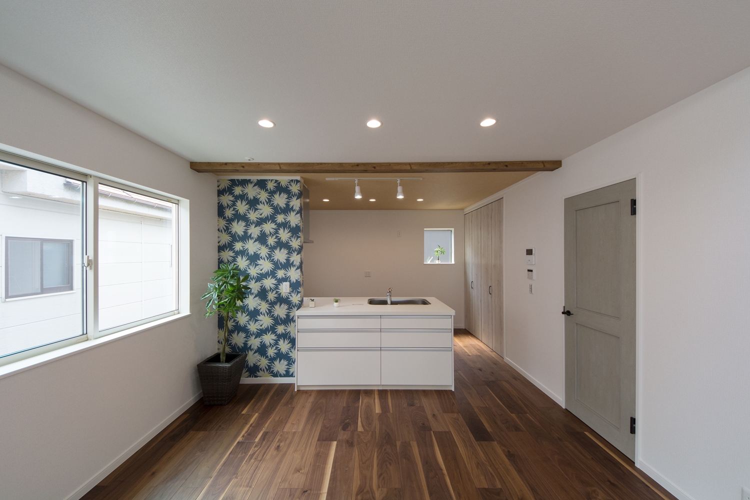 2階LDK/キッチンと壁の白をベースに、フローリングと化粧梁の深い色味がメリハリを与えています。建具や花柄クロスがポイントになってハイセンスな空間に。