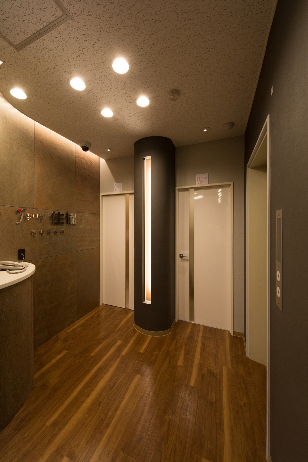 石材を使用した壁と間接照明が空間を彩る、シックで高級感のあるエントランス。