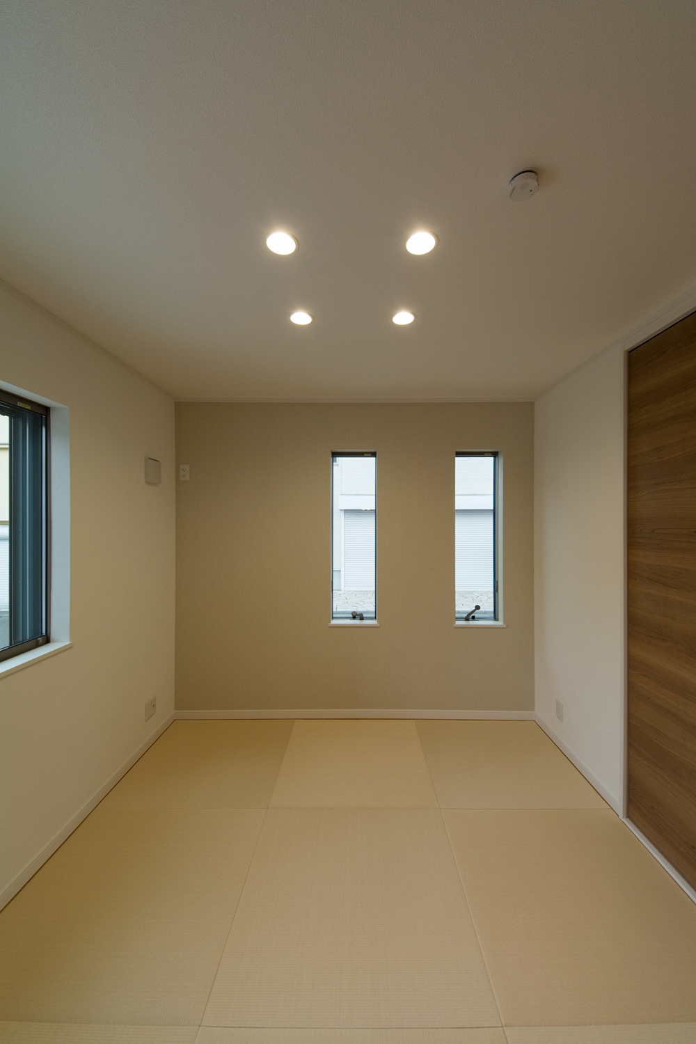アイボリーのアクセントクロスと縁なし畳の優しい色使い。モダンな空間の1F畳敷き洋室。