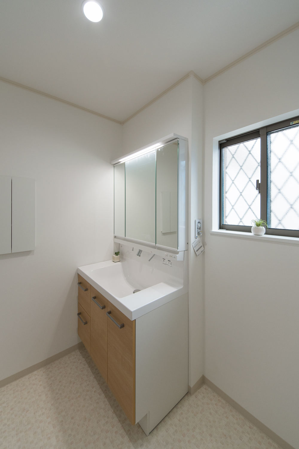 白を基調とした清潔感のあるサニタリールーム。洗面化粧台扉を明るい木目調カラーでアクセント。