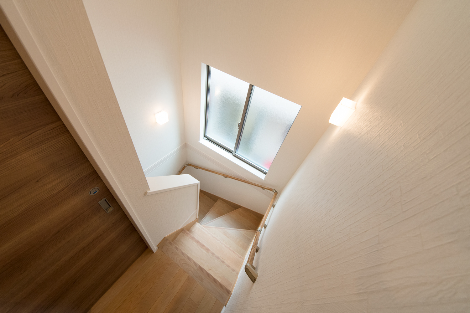 窓からの自然光とブラケットライトのやわらかい光が階段を照らします。