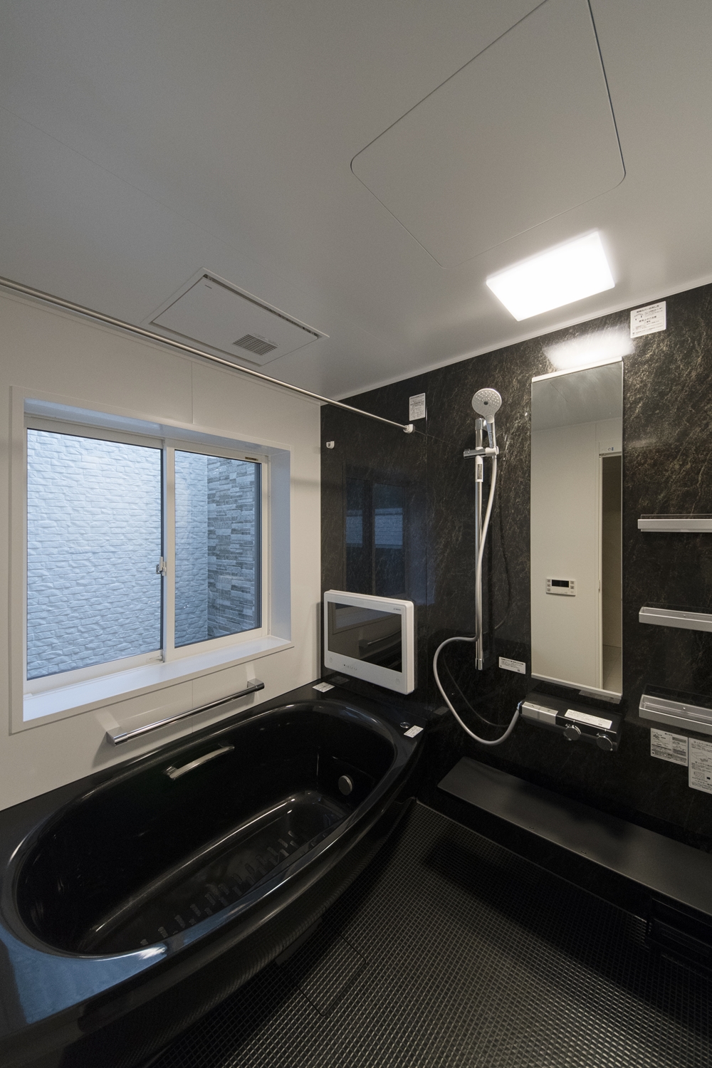 ブラックの石目調アクセントパネルが上質な空間を演出。浴槽カラーもブラックで高級感のある印象のバスルームに。