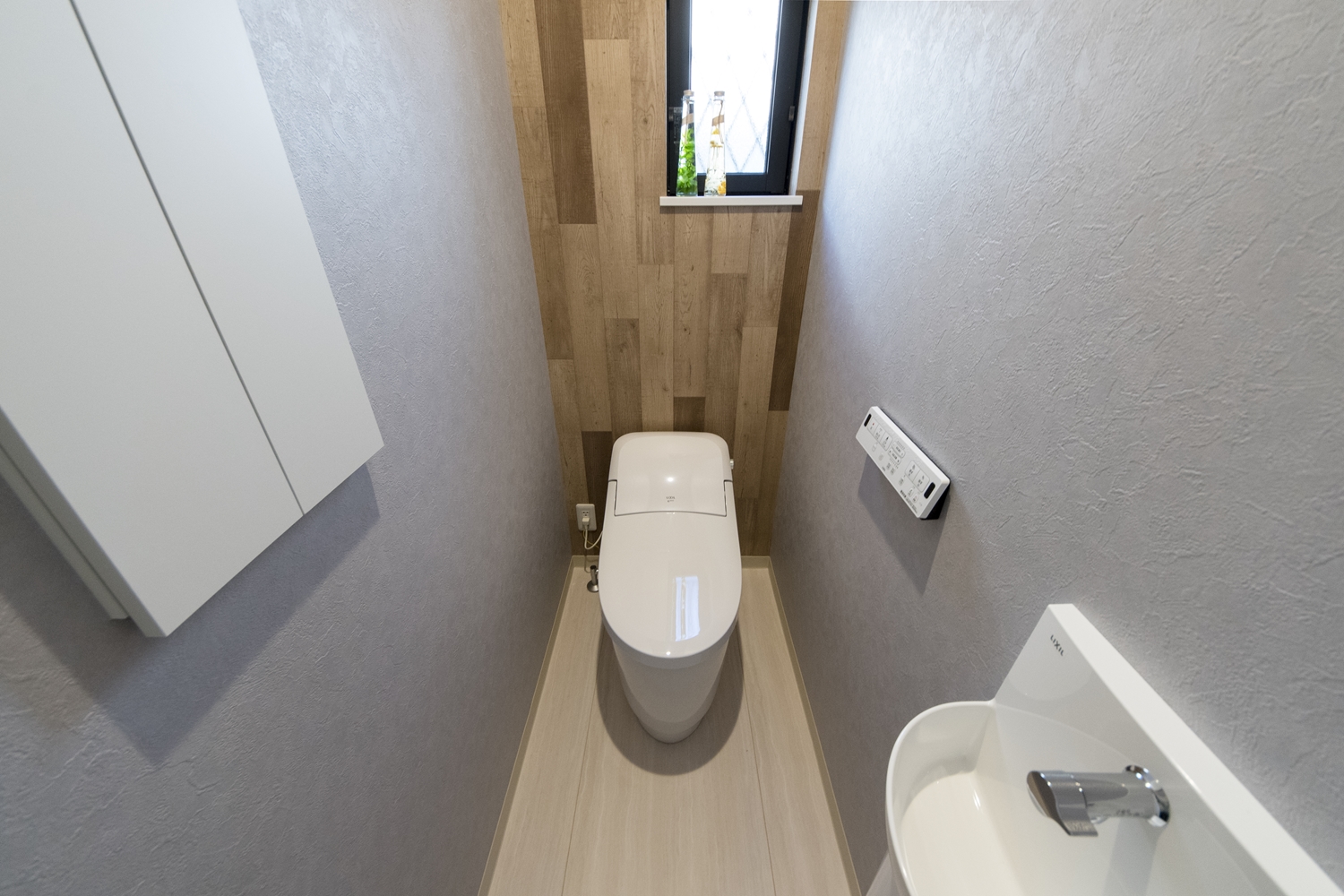 1階トイレ/グレイッシュなクロスと、木の素材感のあるクロスを組み合わせたオシャレな空間。