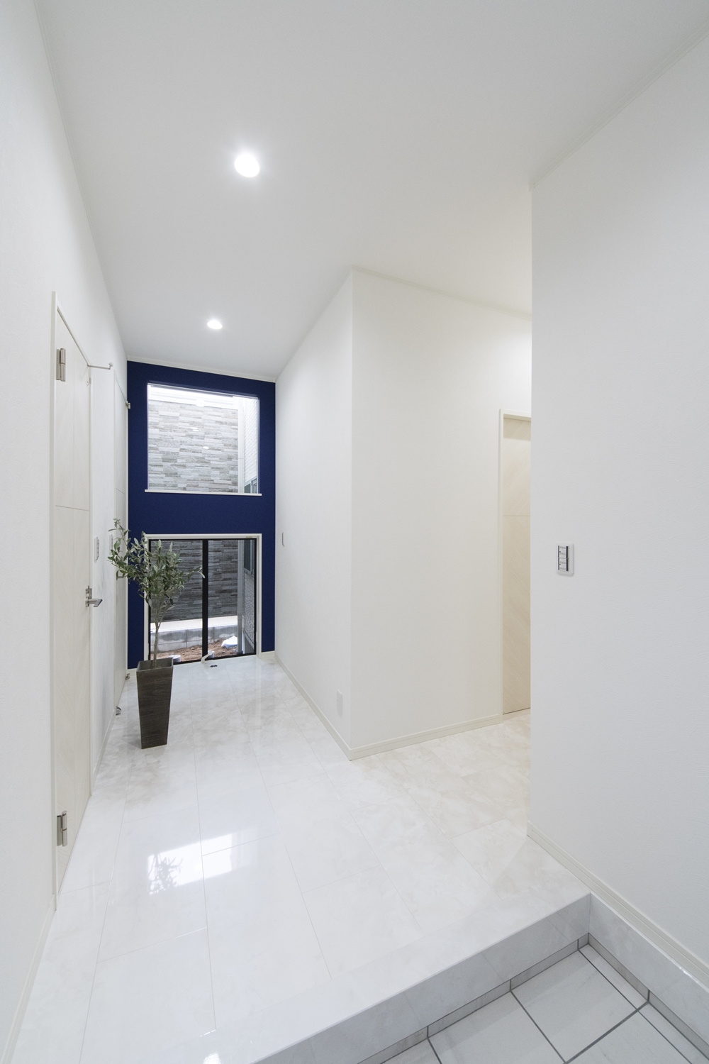 ゲストエントランス／大理石の風合いをリアルに再現した高級感のある白い床。ハイスタッド仕様（CH：2680mm）の開放感ある高い天井。