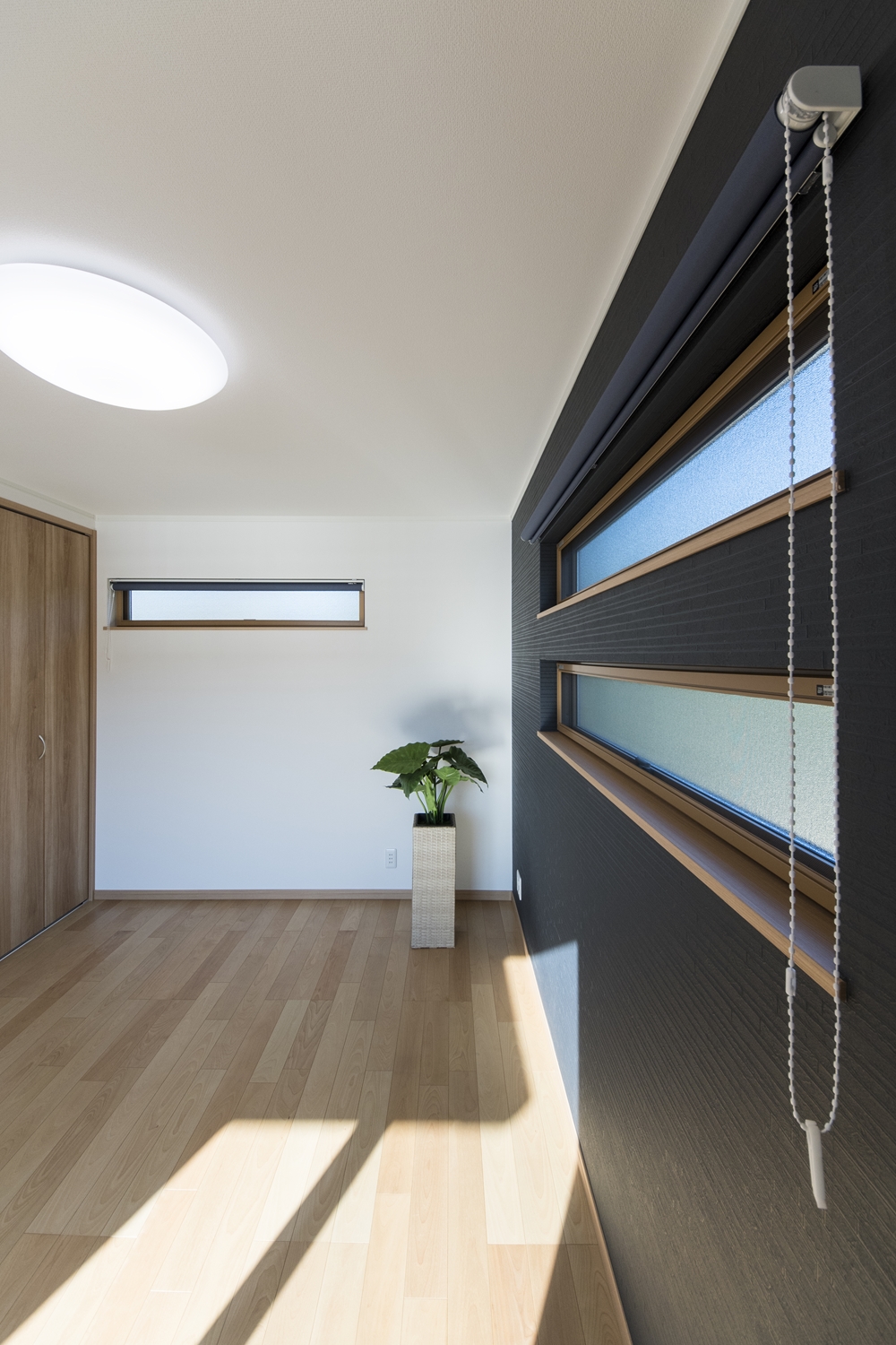 2階洋室／深みある濃紺色の壁紙と二連の横長窓のデザインがスタイリッシュな空間を演出。