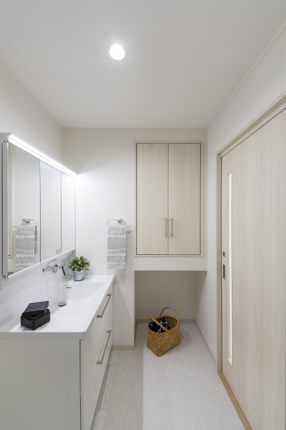 白を基調とした清潔感のあるサニタリールーム。タオルや洗剤等をしまえると扉付の収納を設えました。