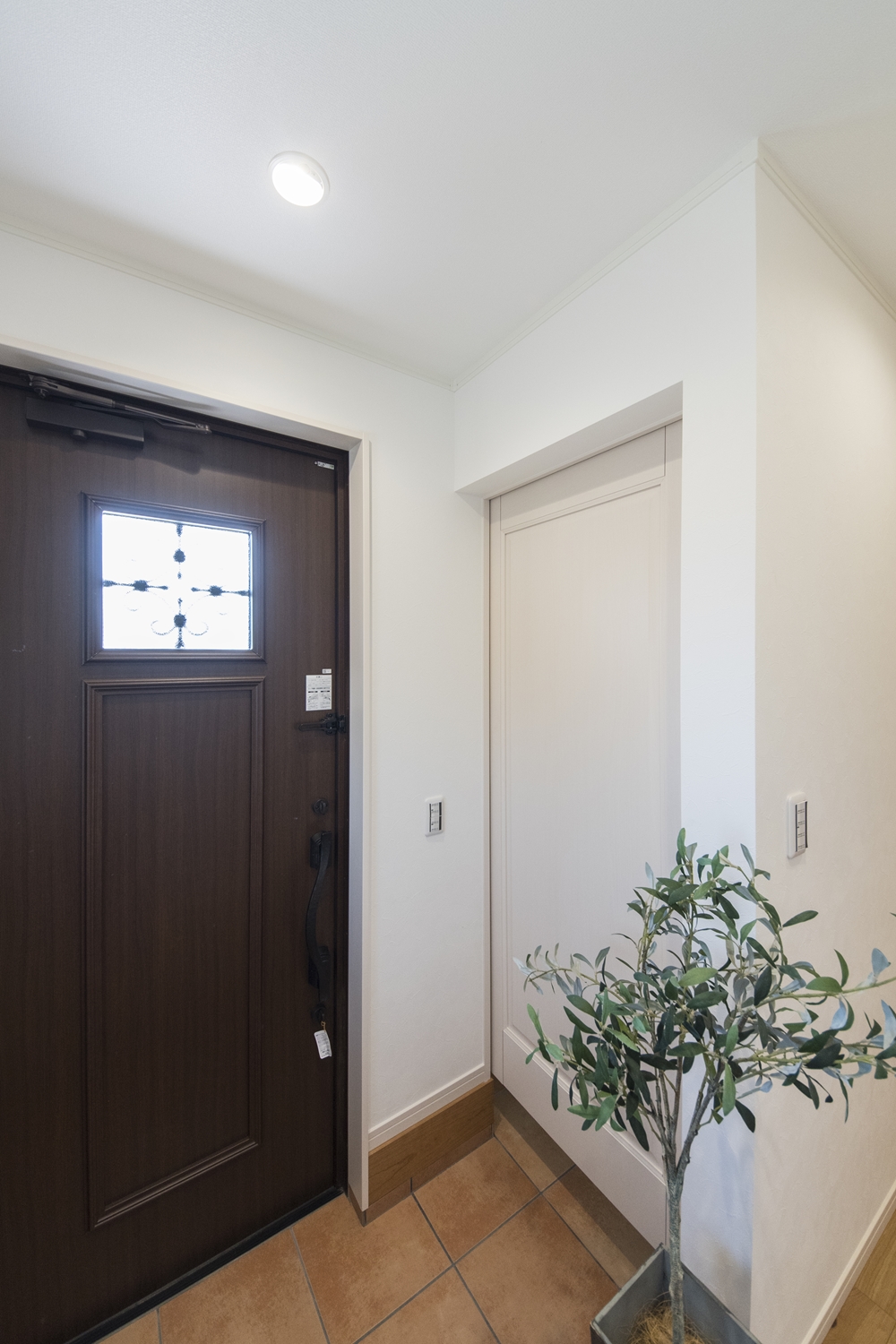 木の温もり感じる玄関ドアや収納、レッドのテラコッタ調タイルがナチュラルテイストな空間を演出。