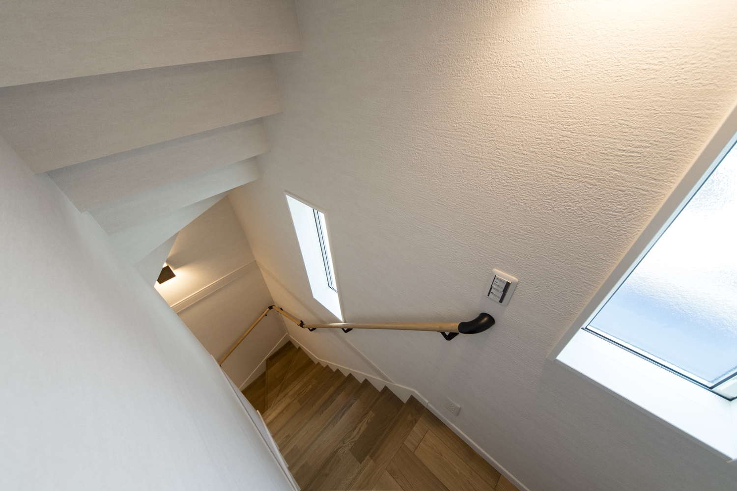 窓からの自然光とブラケットライトのやわらかい光が階段を照らします。