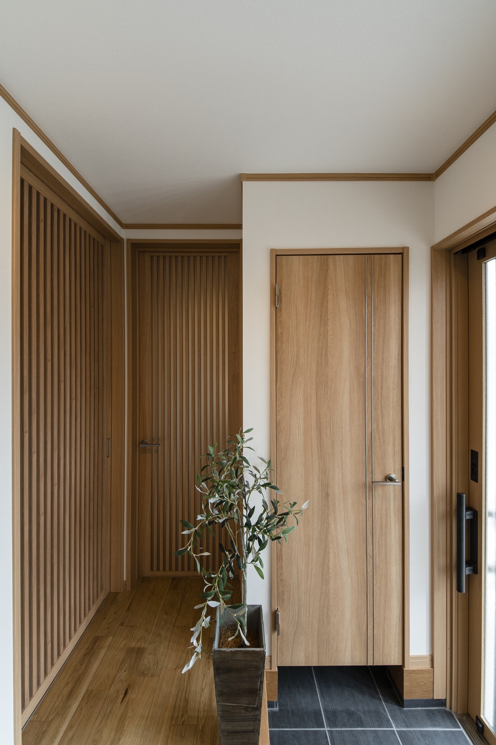 木の温もりを感じる、上質で落ち着いた印象の玄関ホール。無駄のないシャープなラインが気品を添える、スリット格子の建具が目を惹きます。