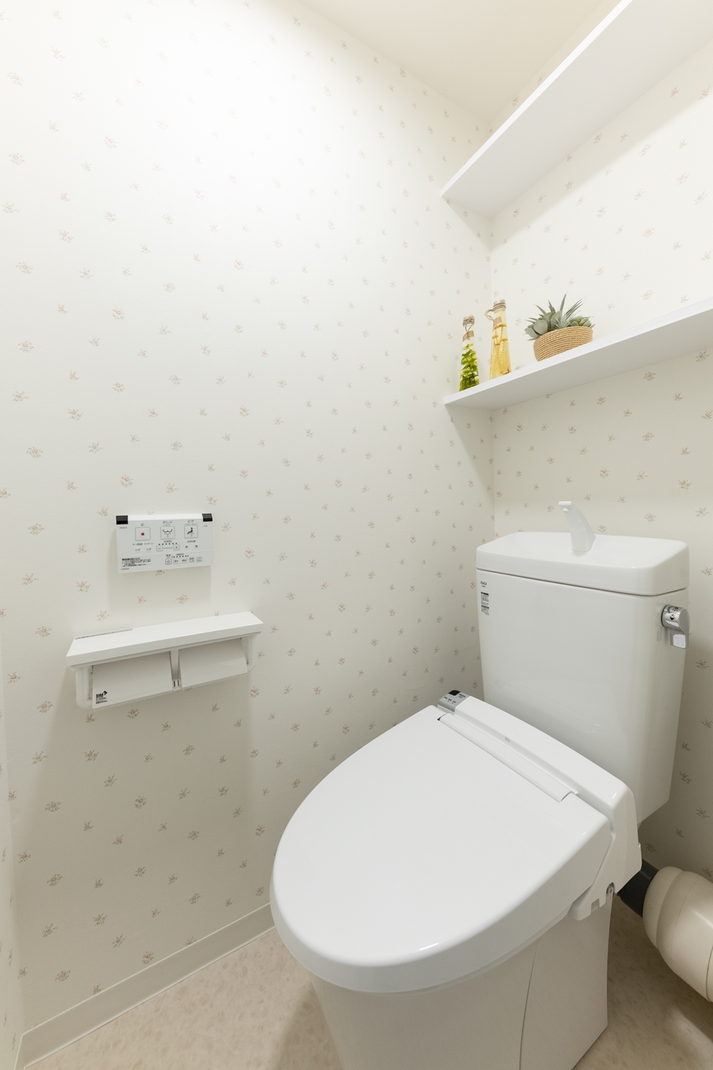 トイレ／花柄の白いクロスが、さり気なくエレガントに清潔感を演出します。ペーパーホルダーやウォシュレットトイレに交換して機能的になりました。