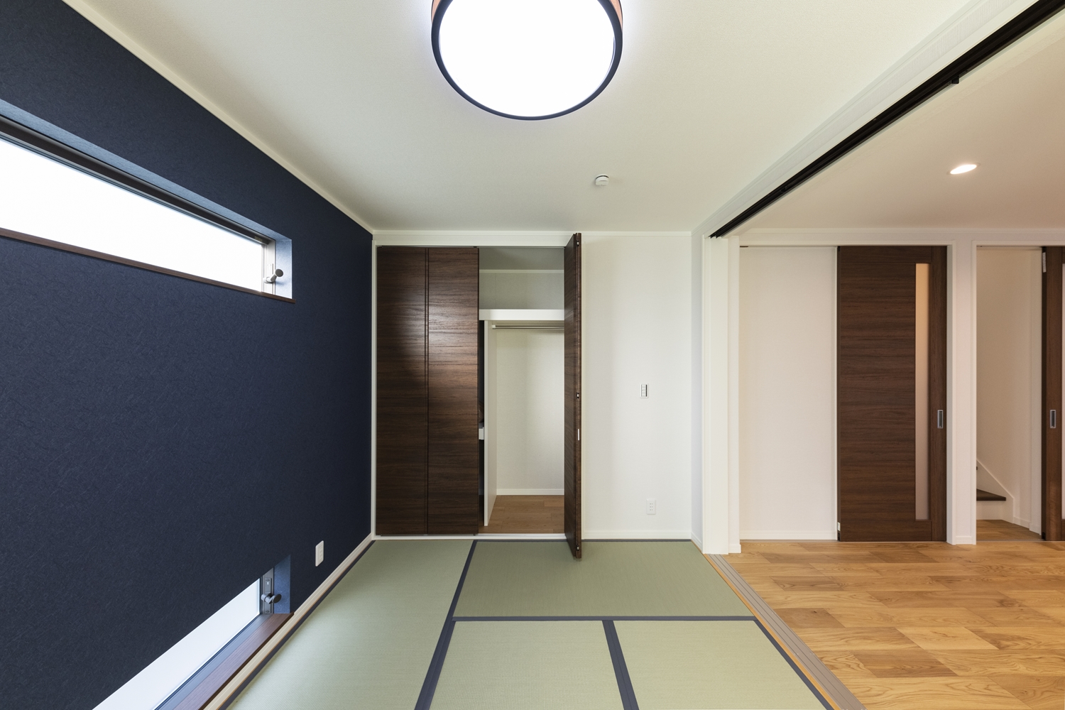 1階畳敷き洋室／濃紺のアクセントクロスや、上下に並べた横窓がモダンな和空間を演出。