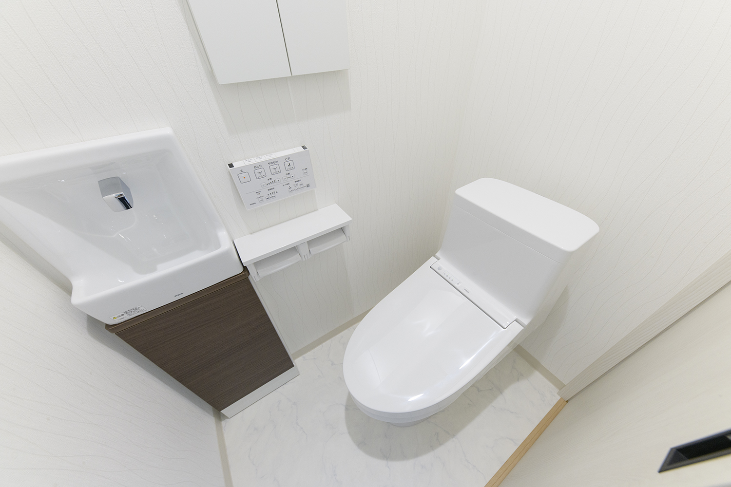 白を基調とした清潔感のある1階トイレ。手洗いや場所をとらないキャビネットを設置して機能的でスッキリとした空間に。